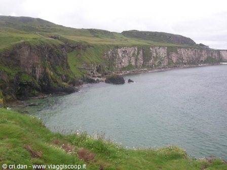 White cliffs above turquoise sea, green grass slopes and rocky shore, causeway coast