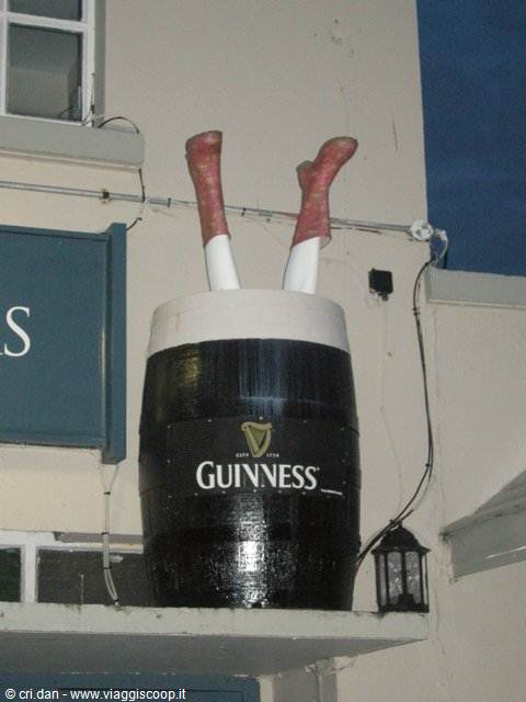Guinness barrel with legs sticking out above an Irish pub