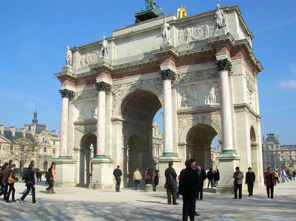 Tourists walk beneath the Arc de Triomphe du Carrousel in Paris