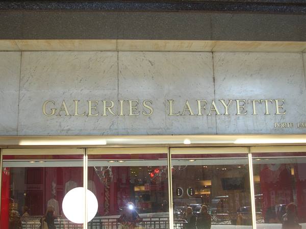 Golden Galeries Lafayette sign on marble facade, lit shop windows below