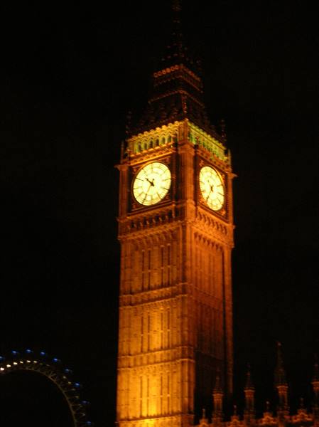 Big Ben lit up at night in London, next to the London Eye