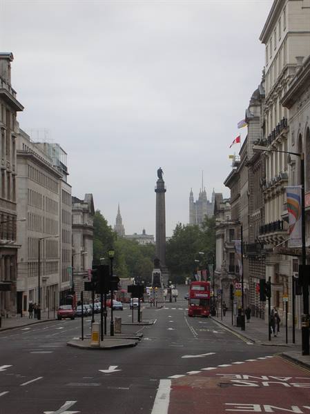 Red bus on Whitehall, London, with the Duke of York Column between grey buildings