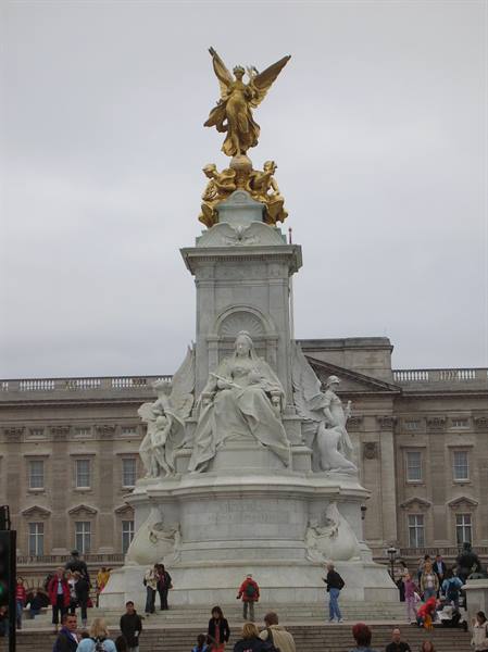 Tourists beneath the Victoria Memorial in front of Buckingham Palace, grey sky
