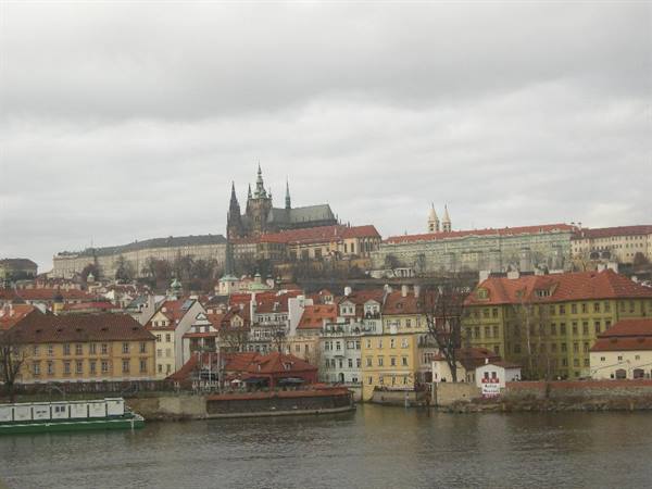 Prague Castle and red-roofed houses above the Vltava under grey sky