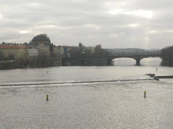 The Vltava river with weir, National Theatre and bridge under Prague's grey sky