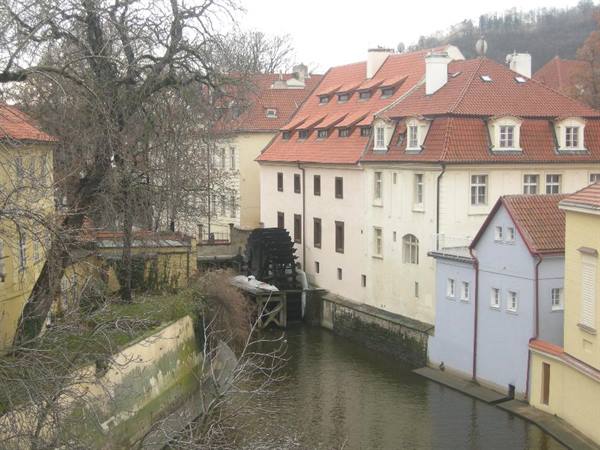 Old wooden waterwheel on the Certovka canal among white houses and red roofs