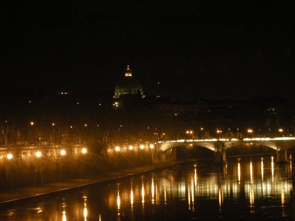At night the Tiber reflects bridge lights, with St. Peter's dome in the background