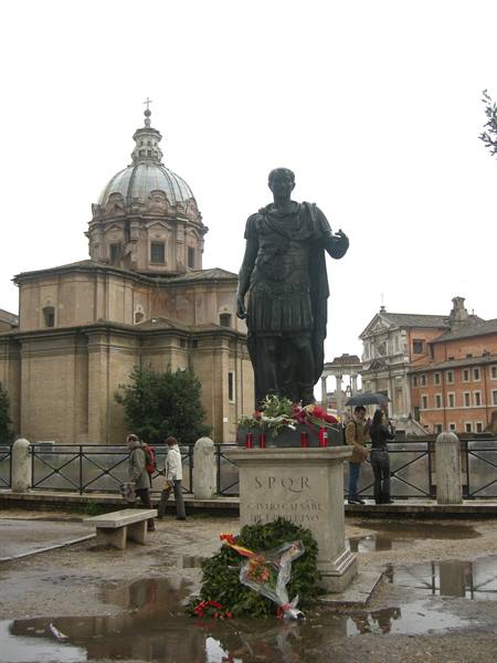 Bronze statue of Caesar with floral wreath, church dome behind, Rome