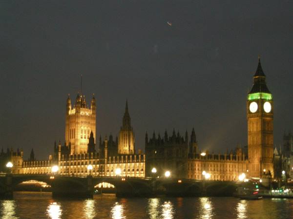 Big Ben and Westminster lit at night, yellow lights reflecting on the Thames