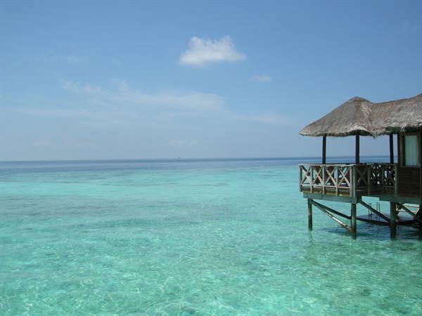 Wooden thatched stilt bungalow over clear turquoise water
