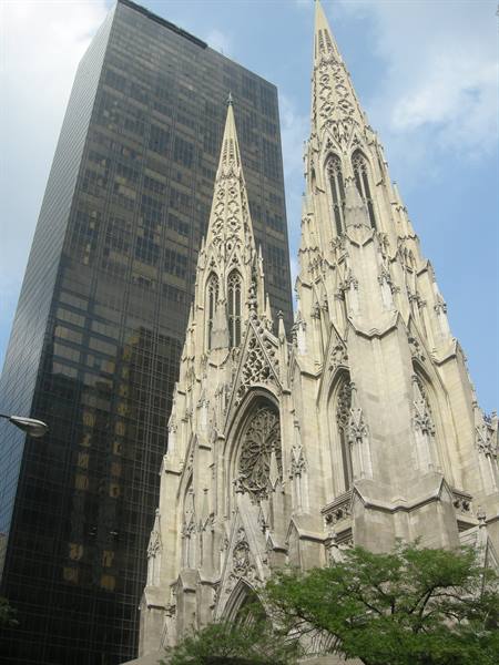 White marble gothic spires of St. Patrick's Cathedral beside a dark skyscraper