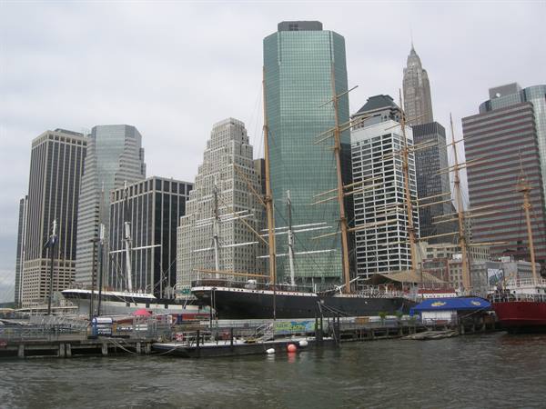 Tall ship moored at South Street Seaport pier, New York, among skyscrapers