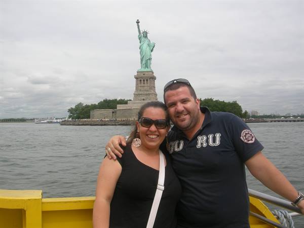 Smiling couple on a ferry boat in front of the Statue of Liberty