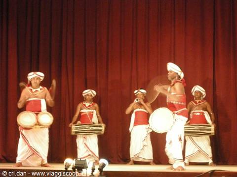 Traditional drummers in white and red costumes play drums on curtained stage
