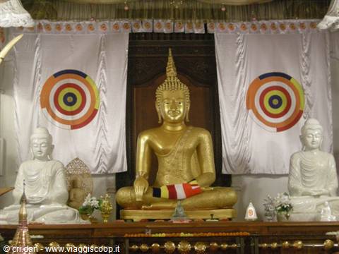 Golden Buddha flanked by white statues inside Dambulla temple