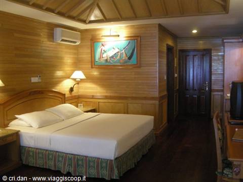 Hotel room with double bed and wooden teak walls