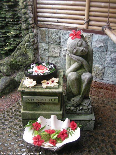 Thoughtful stone statue decorated with hibiscus flowers at Araamu Spa entrance