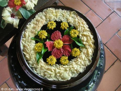 Red and yellow artificial flowers float in a dark stone basin