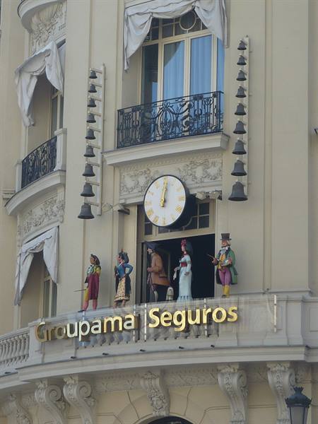 Facade with clock, bells and traditional figurines on a balcony, Groupama Seguros sign