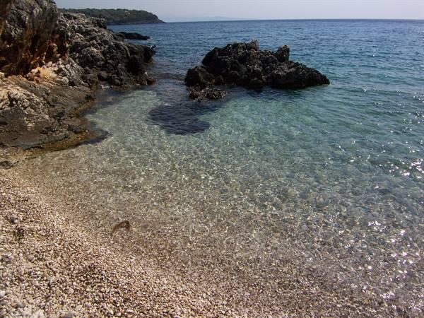 Clear water over white pebbles and dark rocks in an Adriatic cove