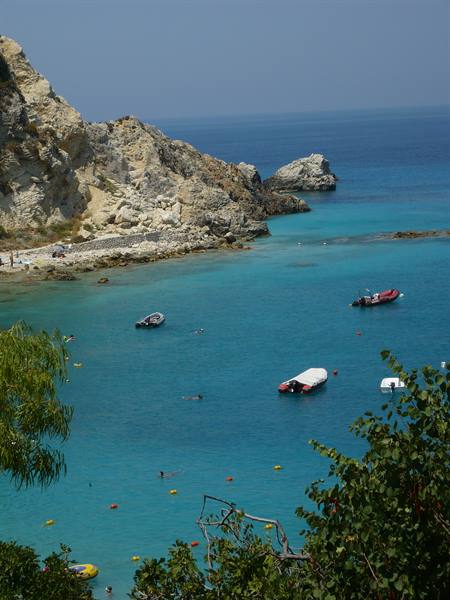 Boats anchored in turquoise bay, limestone cliffs and swimmers