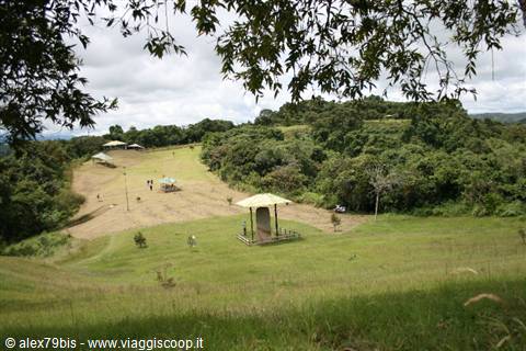 Wooden pavilion and parasols on a green meadow, people strolling around