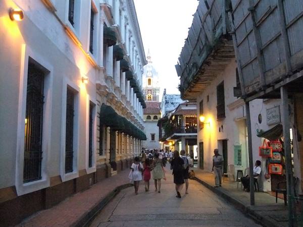 Pedestrians in a Cartagena colonial street with the cathedral dome
