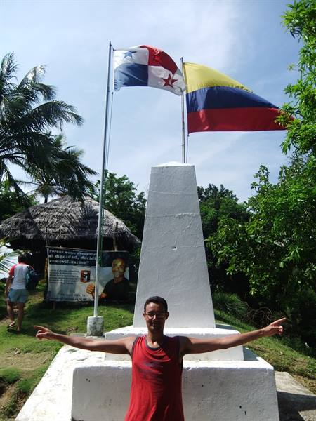 Tourist with open arms beneath Panama and Colombia flags, white obelisk