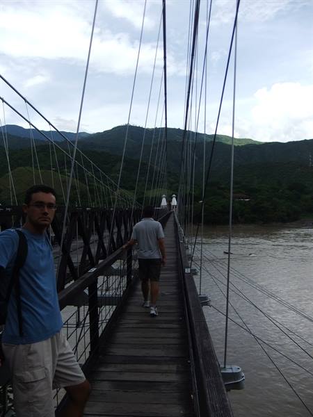 Tourists crossing a wooden suspension bridge with cables over a river