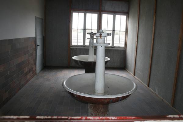 Abandoned circular washbasins in an empty room, light from windows