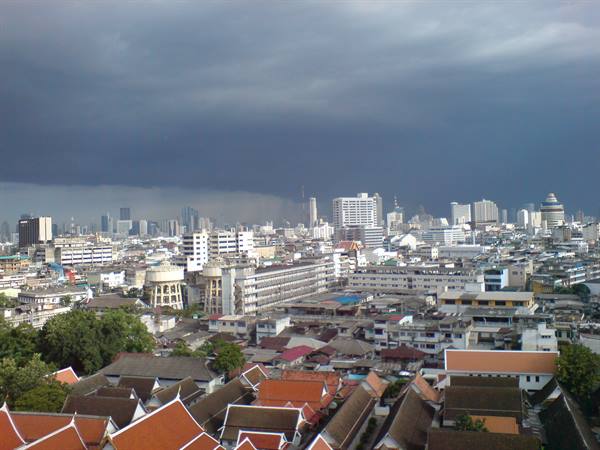 Red temple rooftops under rain clouds over Bangkok