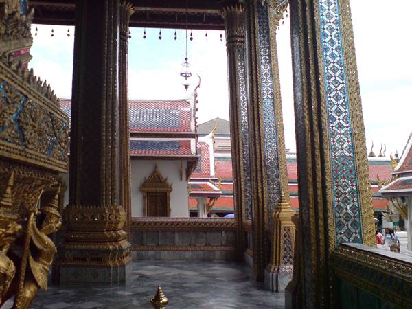 Mirrored mosaic columns and red rooftops at Wat Phra Kaew