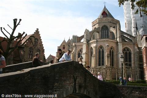 Tourists on stone bridge in front of the medieval church, Bruges
