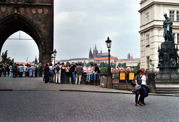 Tourists at Charles Bridge Tower, Prague Castle visible in the background