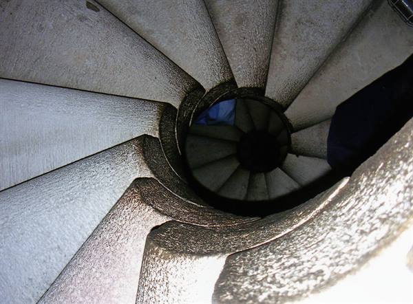 Stone spiral staircase seen from above, pale steps in shadow
