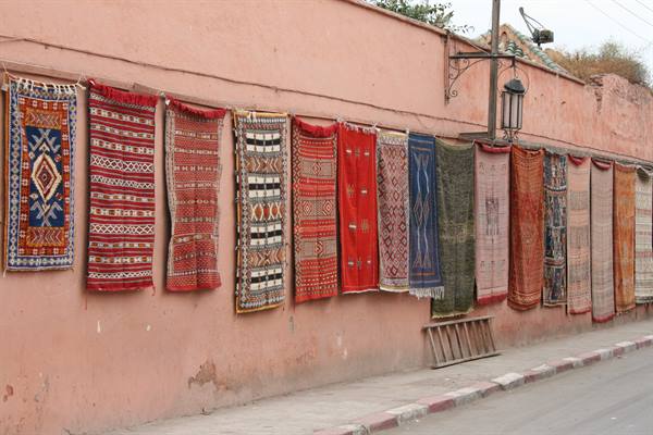 Berber rugs hanging on a pink wall along the street, daylight