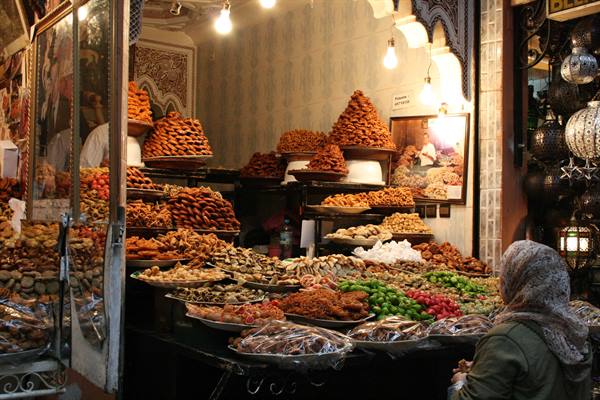 Dried fruit and sweets stall in a souk, veiled woman looking
