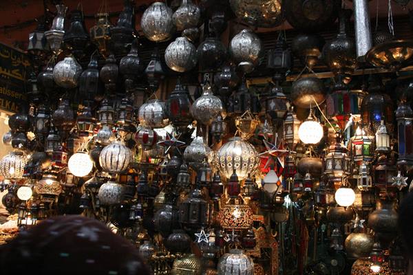 Punched metal lanterns hanging in a souk, warm light glowing among lamps