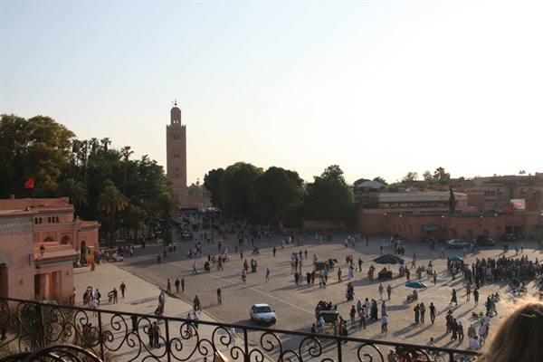Crowded Jemaa el-Fna square with the Koutoubia minaret rising on the left