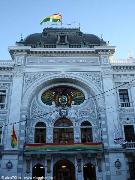 Ornate white palace with Bolivian flag and La Unión es la Fuerza inscription