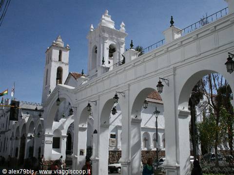 White colonial church with two bell towers and arched arcade, people strolling