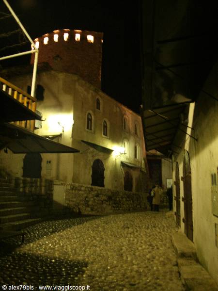 Cobblestone alley at night with illuminated stone tower