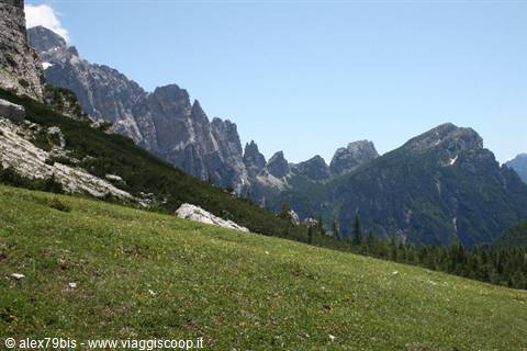 Grassy slopes beneath jagged Dolomites peaks, blue sky