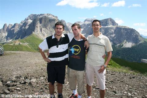 Three friends embracing at a mountain pass, Dolomites peaks behind