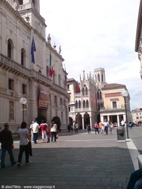 Pedestrians in a Padua square between a flag-adorned palace and Pedrocchi café