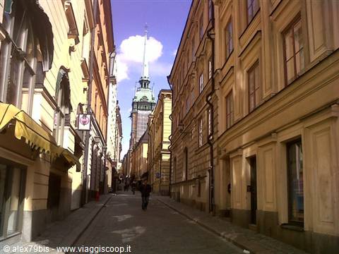 Narrow street in Stockholm, Gamla Stan, with the green spire of Tyska kyrkan