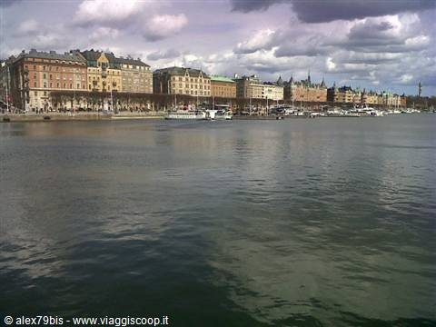Nineteenth-century façades along Stockholm's waterfront, moored boats under dark clouds