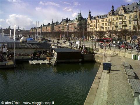 Floating baths and boardwalk along Strandvägen, ornate buildings, people strolling in sunshine