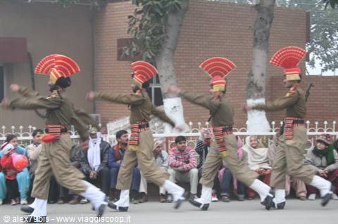 Guards in khaki uniforms and tall red headdresses marching at the Wagah ceremony