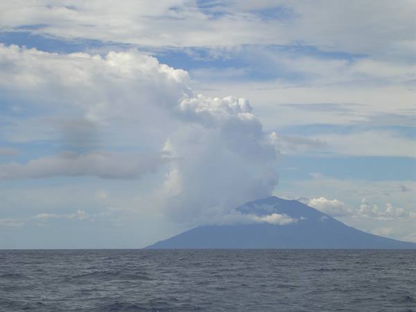 Stromboli volcano releasing white smoke above the blue sea